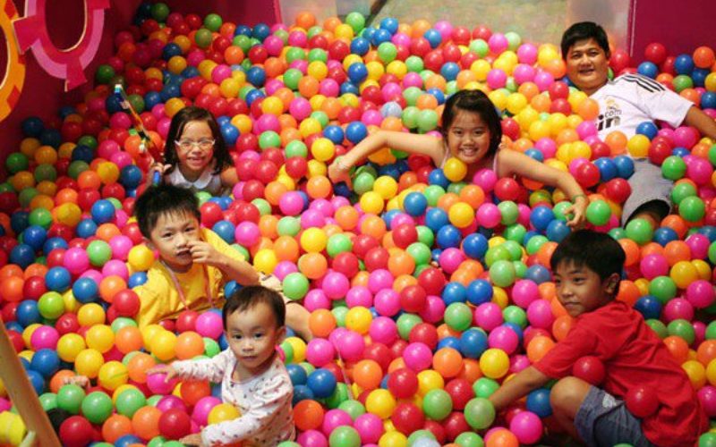 Bé cầm đồ chơi dùng chung ở khu vui chơi trẻ em